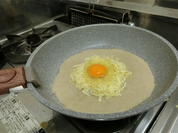 ④　フライパンに油をひき生地を入れ伸ばし、チーズで土手を作り、そこに卵を割り入れる